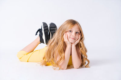 Studio portrait pretty girl with curly hair sitting on floor in studio smiling