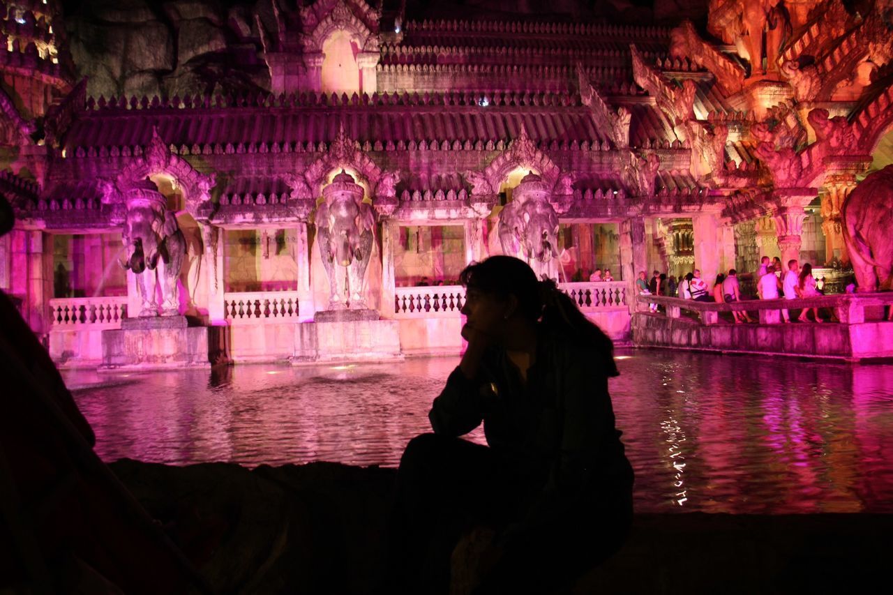 WOMAN SITTING WITH ILLUMINATED LIGHTS IN WATER