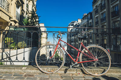 Bicycles parked by railing against buildings in city