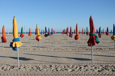 Row of flags on beach against clear blue sky