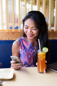 Young woman using phone in restaurant