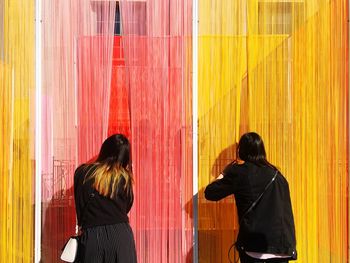 Rear view of woman standing against multi colored wall