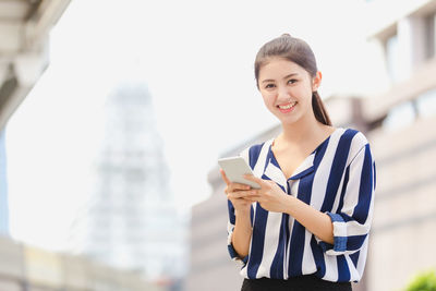 Portrait of smiling young woman using smart phone