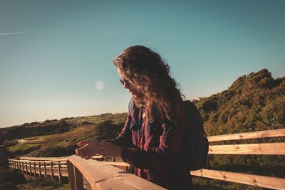 Woman standing on boardwalk against clear sky