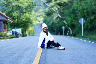 Portrait of smiling woman sitting on road