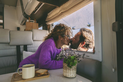 Romantic couple kissing each other through camping van window