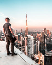 Man standing by modern buildings against sky in city