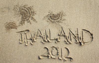 High angle view of thailand 2012 written on sandy beach