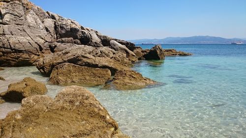 Rock formation in sea against clear sky