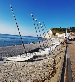 Sailboats moored on beach against clear blue sky