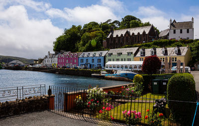 Buildings by river against sky in town