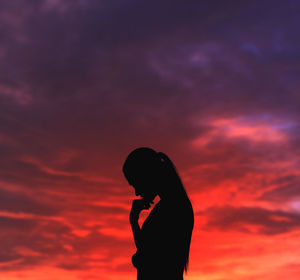 Silhouette woman standing against orange sky