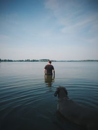 Rear view of man with dog standing in sea