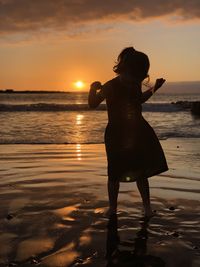 Woman standing at beach during sunset