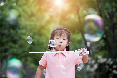 Cute girl blowing bubbles outdoors