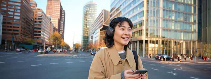 Portrait of young woman standing in city