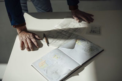 Hands of architect by blueprint on desk in office