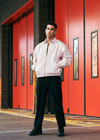 Portrait of young man standing against building