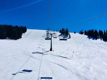 Ski lift over snow covered mountains against sky