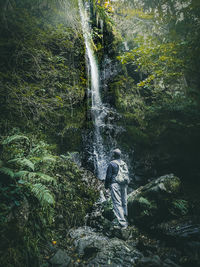 Full length of woman standing on rock in forest