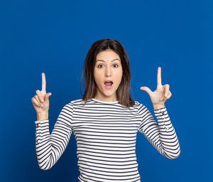 Portrait of young woman standing against blue background