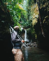 Side view of man standing against waterfall