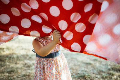 Midsection of woman holding umbrella while standing on field