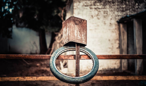 Close-up of tire and rusty metallic container on railing