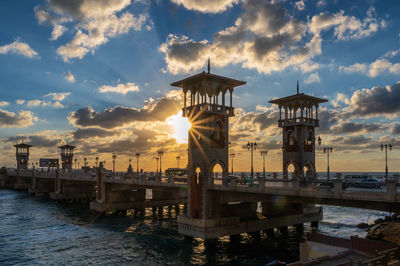 Pier on river against sky during sunset