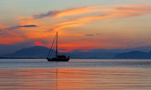 Silhouette ship in sea against sky during sunset