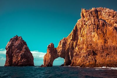 Rock formations in sea against clear sky