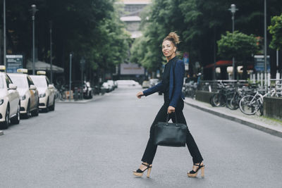 Portrait of young woman standing on road in city