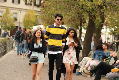 Young friends walking on footpath in city