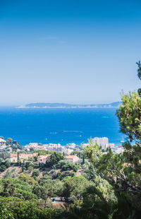 High angle view of townscape by sea against clear blue sky