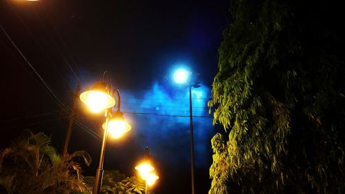 Illuminated street light against sky at night