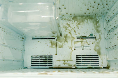 Dirty freezer of modern frigerator with splash of carbonated drink