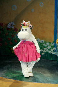 Midsection of girl wearing pink dress standing against wall