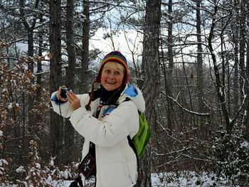 Portrait of smiling young woman standing on snow covered land