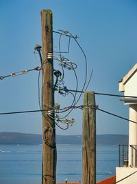 Low angle view of telephone pole against clear blue sky