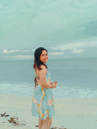 Portrait of smiling young woman standing on beach