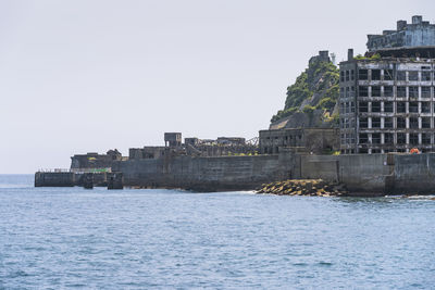 Sea by buildings against clear sky