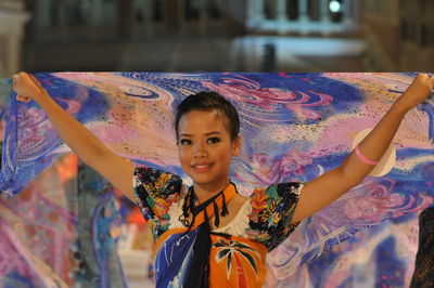 Smiling artist performing traditional dance with scarf during carnival