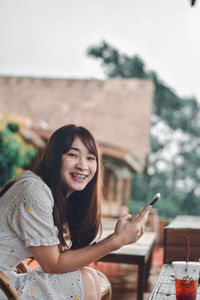 Portrait of a smiling young woman using smart phone