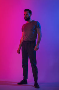 Full length of man standing against pink background