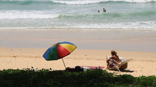 People sitting on beach against sea