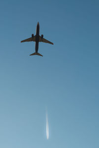 Low angle view of airplane flying against clear blue sky