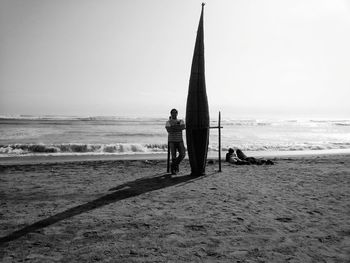 People standing on beach against clear sky