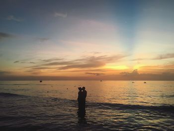 Silhouette people standing on beach against sky during sunset