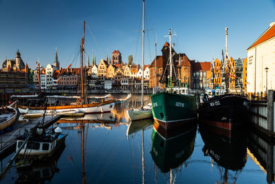 Boats moored at harbor against clear sky