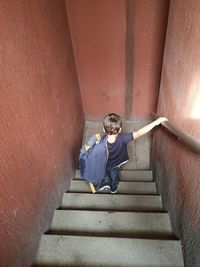 Rear view of boy on staircase against wall